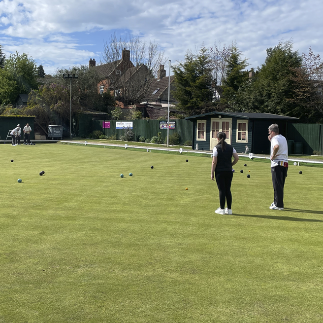 Young female playing grass lawn bowls